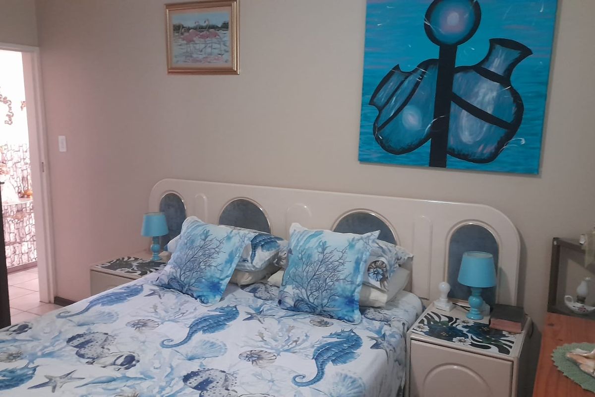 A bedroom featuring a built-in headboard and integrated bedside tables, with a doorway leading to an adjacent bathroom.