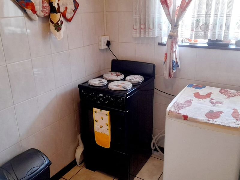 A functional kitchen area featuring tiled walls, tiled flooring, and a freestanding stove, providing a practical space for cooking and utility tasks.