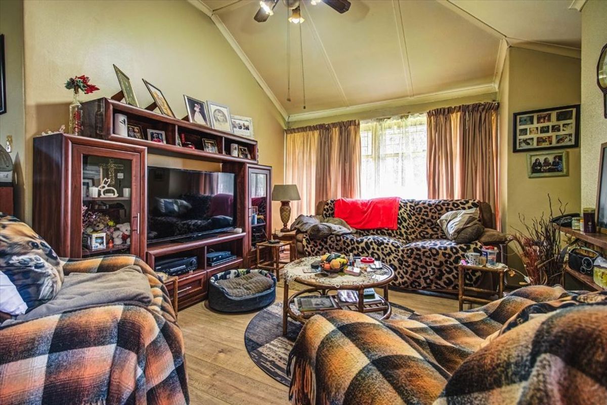 A cozy living room featuring a vaulted ceiling, ceiling fan, and laminate flooring, providing a comfortable and functional living space.