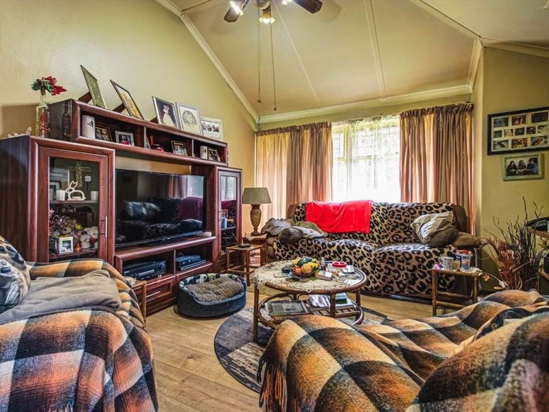 A cozy living room featuring a vaulted ceiling, ceiling fan, and laminate flooring, providing a comfortable and functional living space.