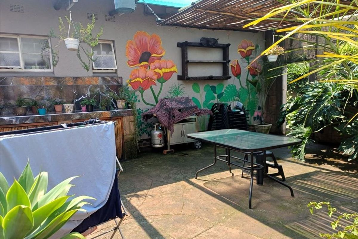Covered outdoor patio area featuring a built-in counter with tiled splashback and decorative wall mural, providing a functional space for outdoor entertaining.