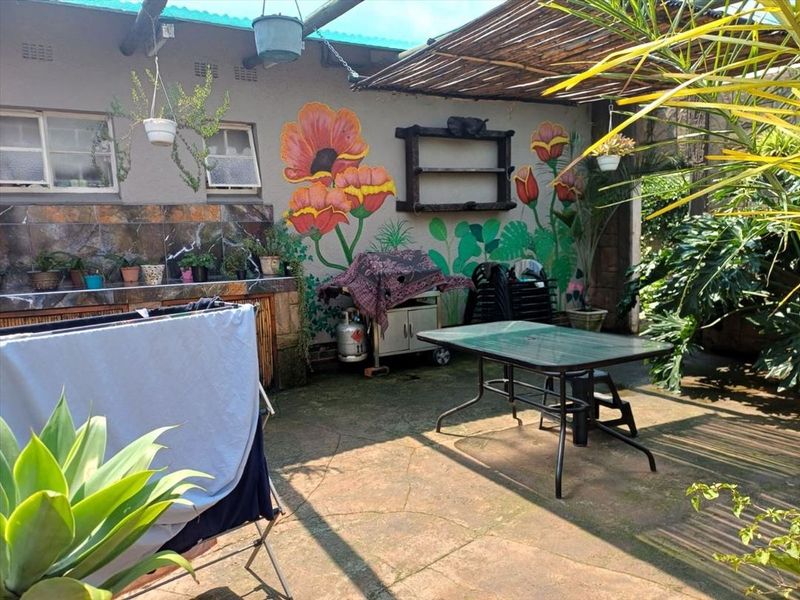 Covered outdoor patio area featuring a built-in counter with tiled splashback and decorative wall mural, providing a functional space for outdoor entertaining.