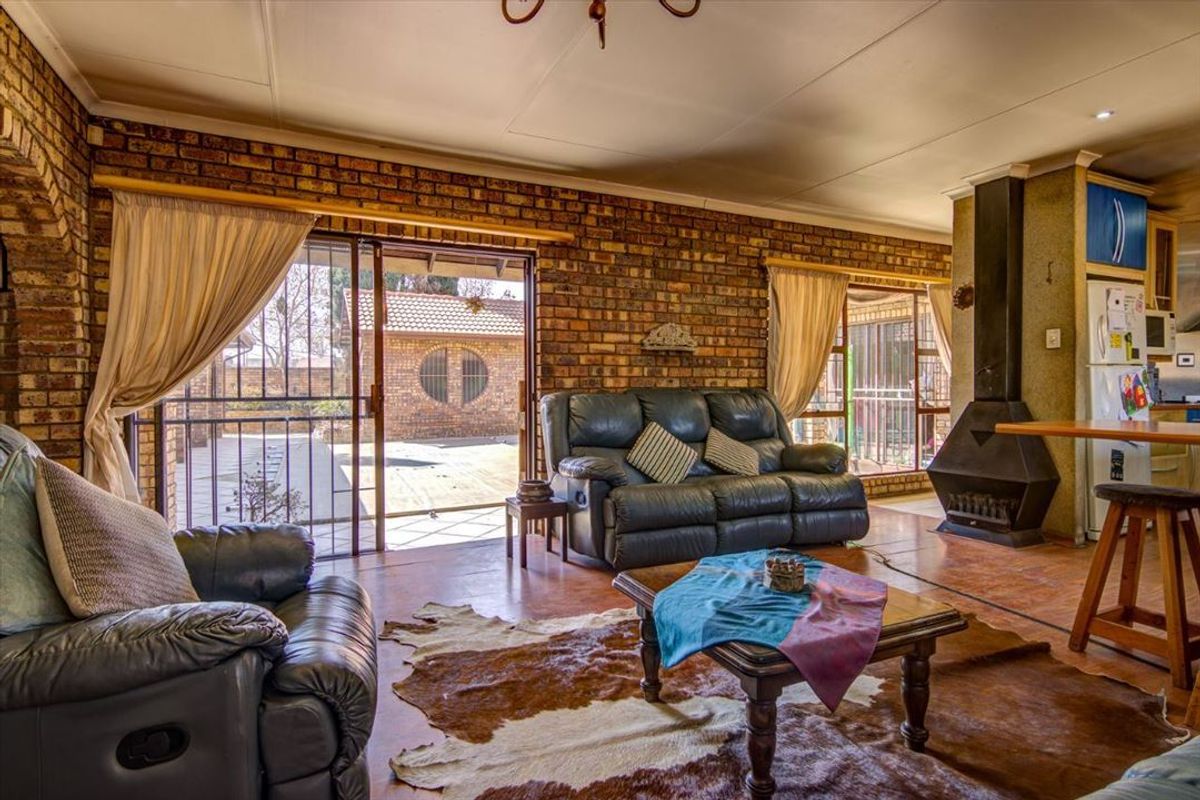 Open-plan living area featuring exposed brick walls, a freestanding fireplace, and sliding glass doors providing direct access to the outdoor patio area.