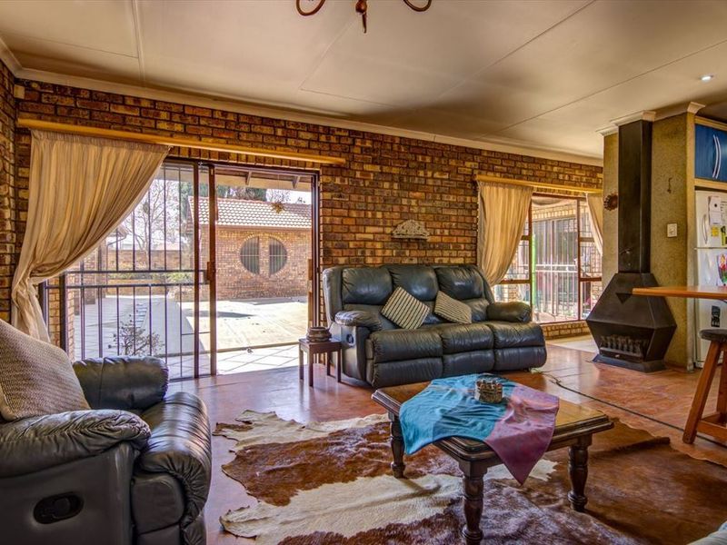 Open-plan living area featuring exposed brick walls, a freestanding fireplace, and sliding glass doors providing direct access to the outdoor patio area.