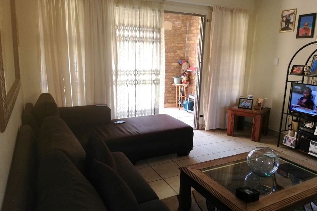 A living room featuring tiled flooring and a sliding glass door providing access to an outdoor patio area.