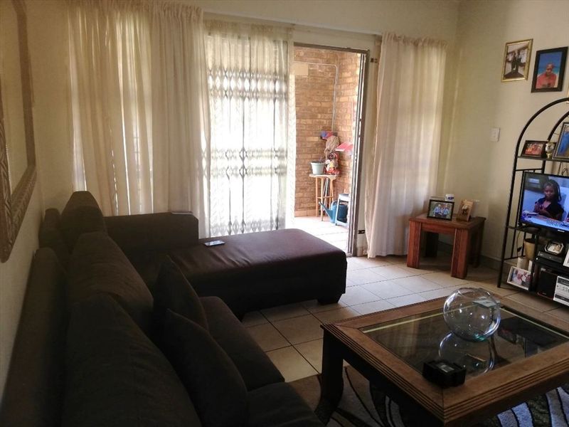A living room featuring tiled flooring and a sliding glass door providing access to an outdoor patio area.