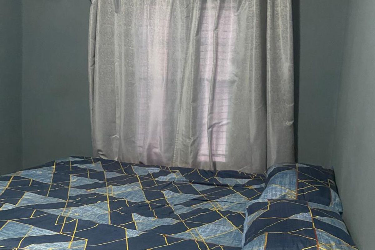 A bedroom featuring dark painted walls, crown molding, and a ventilation grille, providing a functional space for rest.