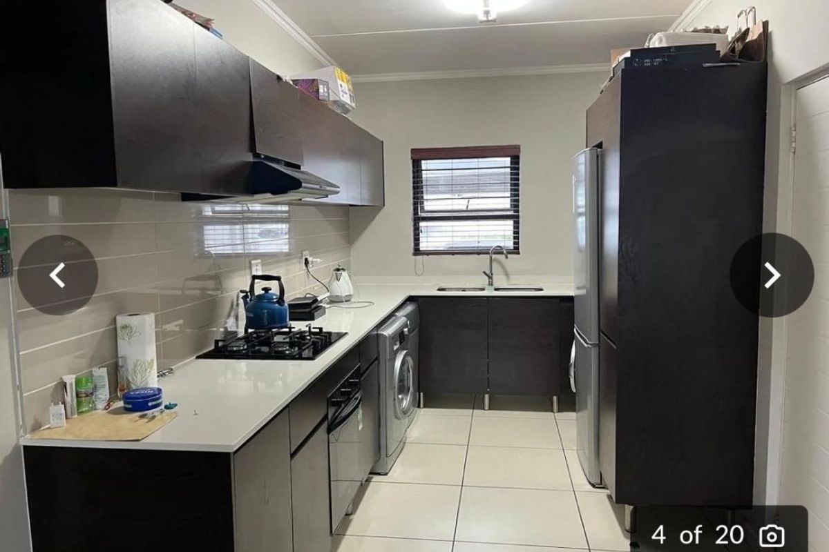 A functional kitchen featuring dark wood cabinetry, stone countertops, a gas hob, and integrated appliances with a clean tiled backsplash and flooring.