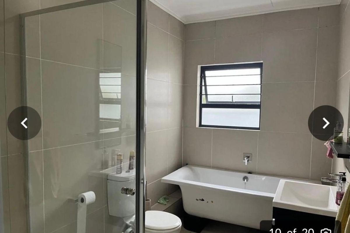 A modern bathroom featuring a freestanding bathtub, a separate glass-enclosed shower, a vanity, and neutral wall tiling.