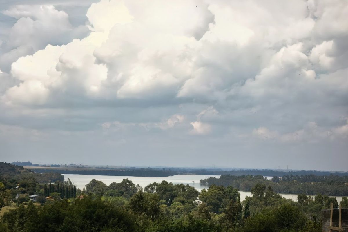A scenic elevated view overlooking a large body of water surrounded by lush greenery and trees under a cloudy sky.