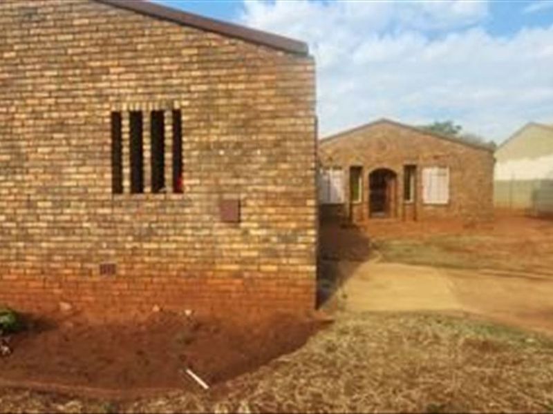 Front view of a face brick house featuring security bars on windows and an unlandscaped yard area.