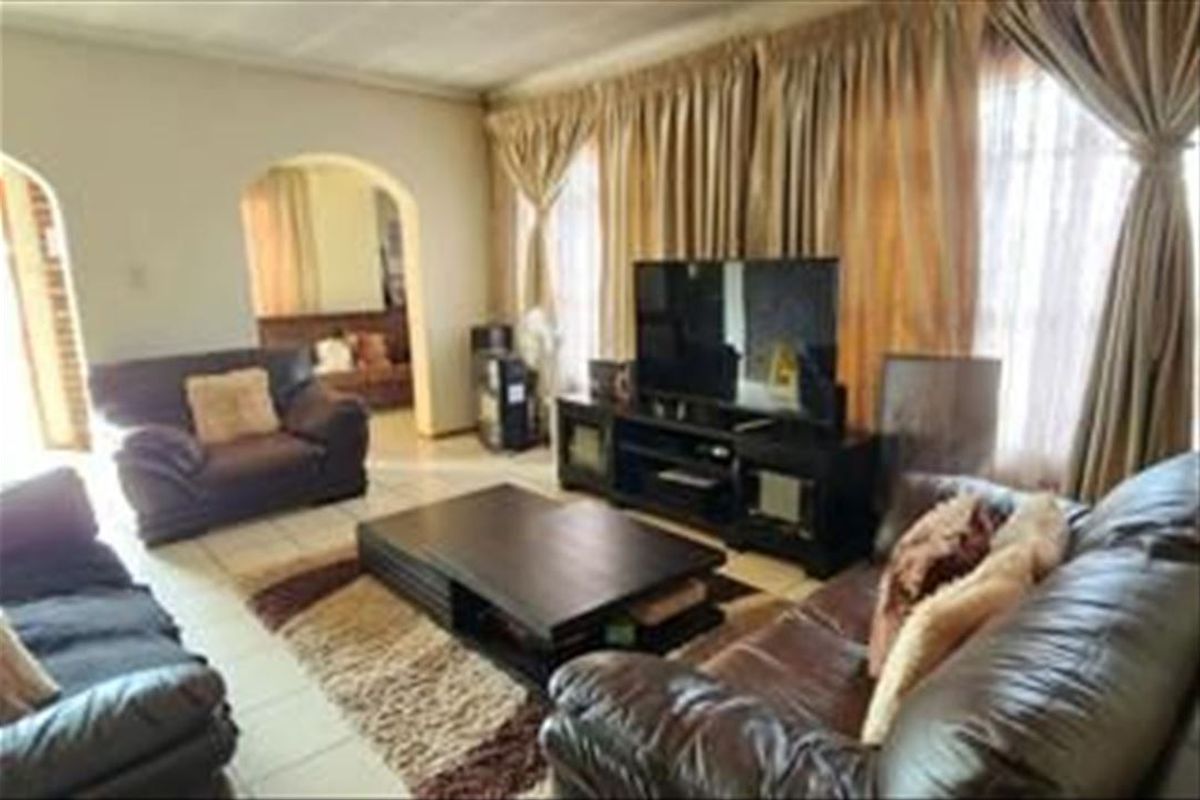 A spacious living room featuring tiled flooring and arched architectural doorways leading to adjacent living areas.