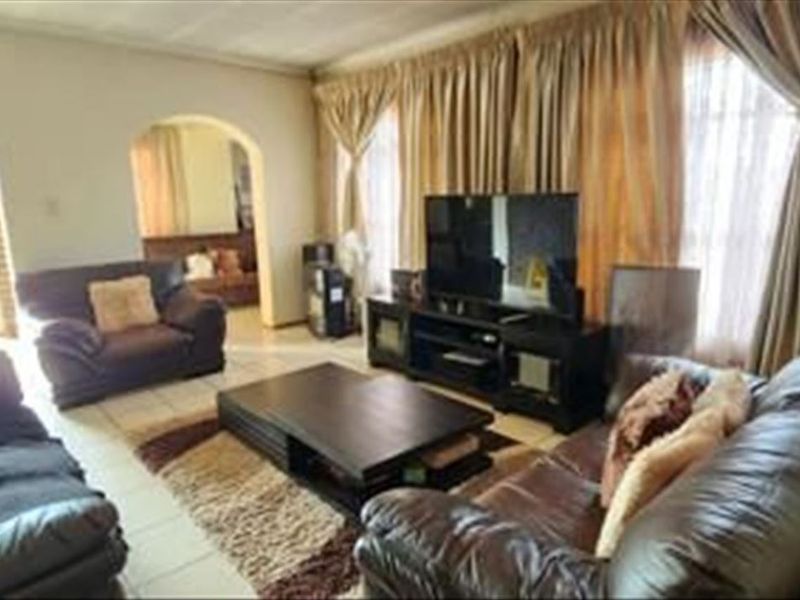 A spacious living room featuring tiled flooring and arched architectural doorways leading to adjacent living areas.