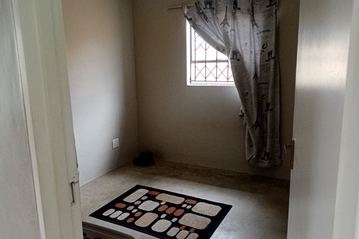 A small, vacant bedroom featuring a security gate on the window and neutral wall finishes, ready for renovation or staging.