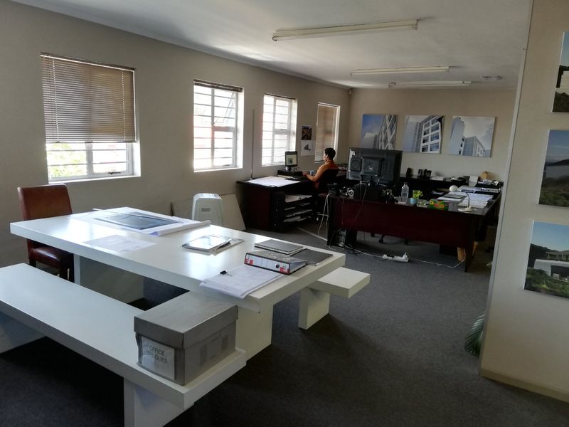 Spacious commercial office area featuring large windows, neutral wall finishes, and functional workspace layout suitable for a professional team environment.
