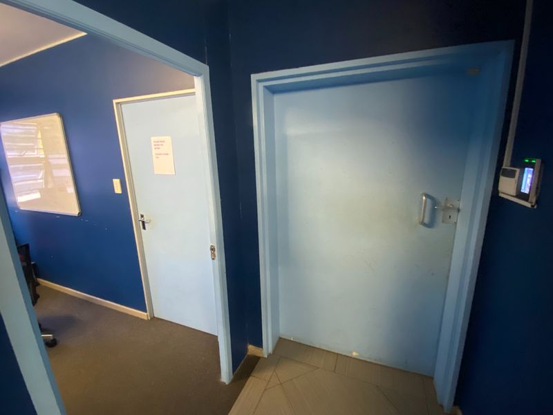 A commercial hallway featuring blue painted walls, two internal doors, and a wall-mounted security access control system.