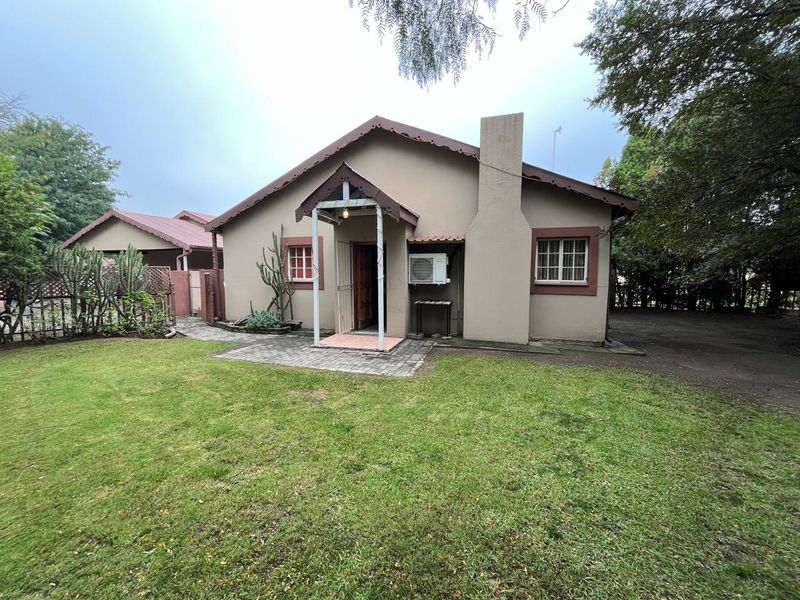 A single-story residential property featuring a covered entrance, exterior chimney, and a well-maintained lawn area.