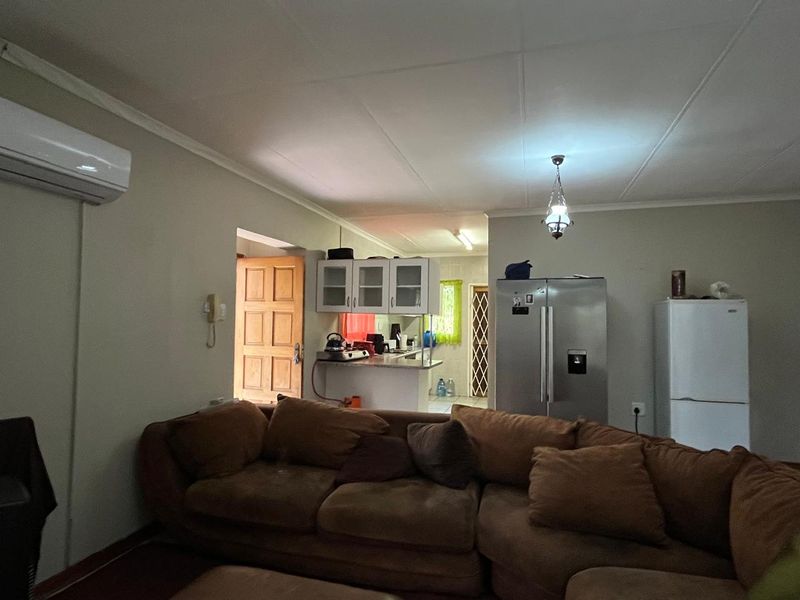 Open plan living area featuring a split-system air conditioner and a functional kitchen space with built-in cabinetry and countertops.