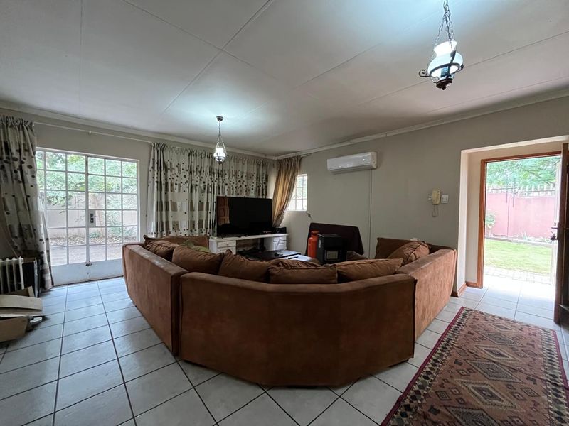 Spacious living room featuring tiled flooring, a split-system air conditioner, and direct access to the outdoor area through glass panelled doors.