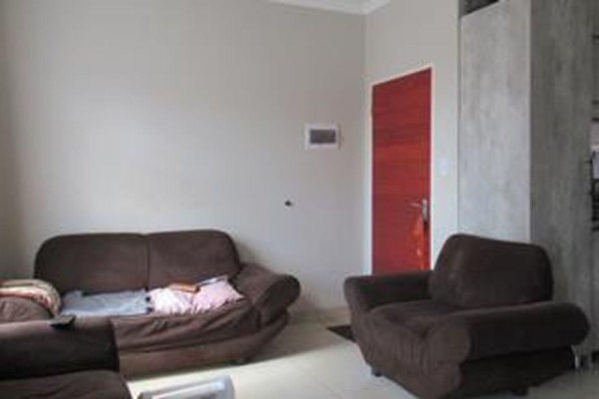 A living room area featuring tiled flooring and a distinctive red interior door.