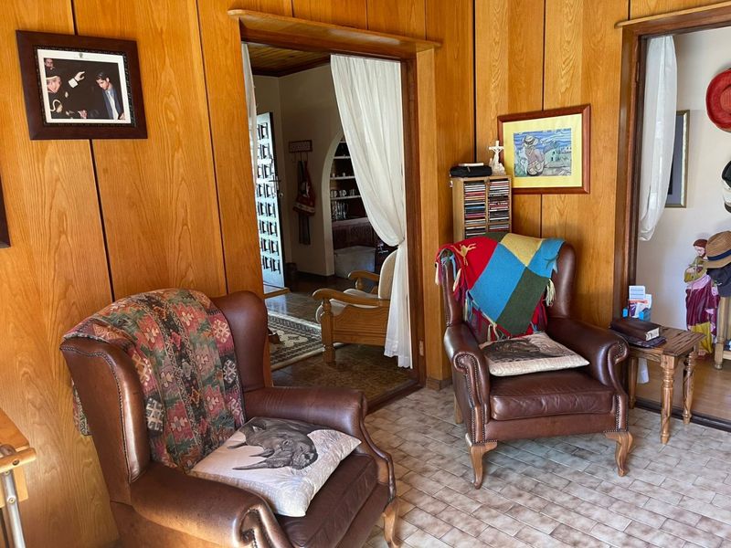 A living room featuring traditional wood paneling on the walls and tiled flooring, with an archway leading to an adjacent room.