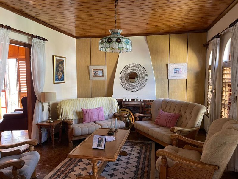 A traditional living room featuring a timber-clad ceiling, a built-in fireplace with a feature wall, and tiled flooring.