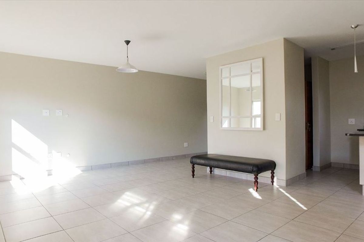 Spacious open-plan living area featuring neutral tiled flooring and modern pendant lighting, seamlessly connecting to the kitchen space.