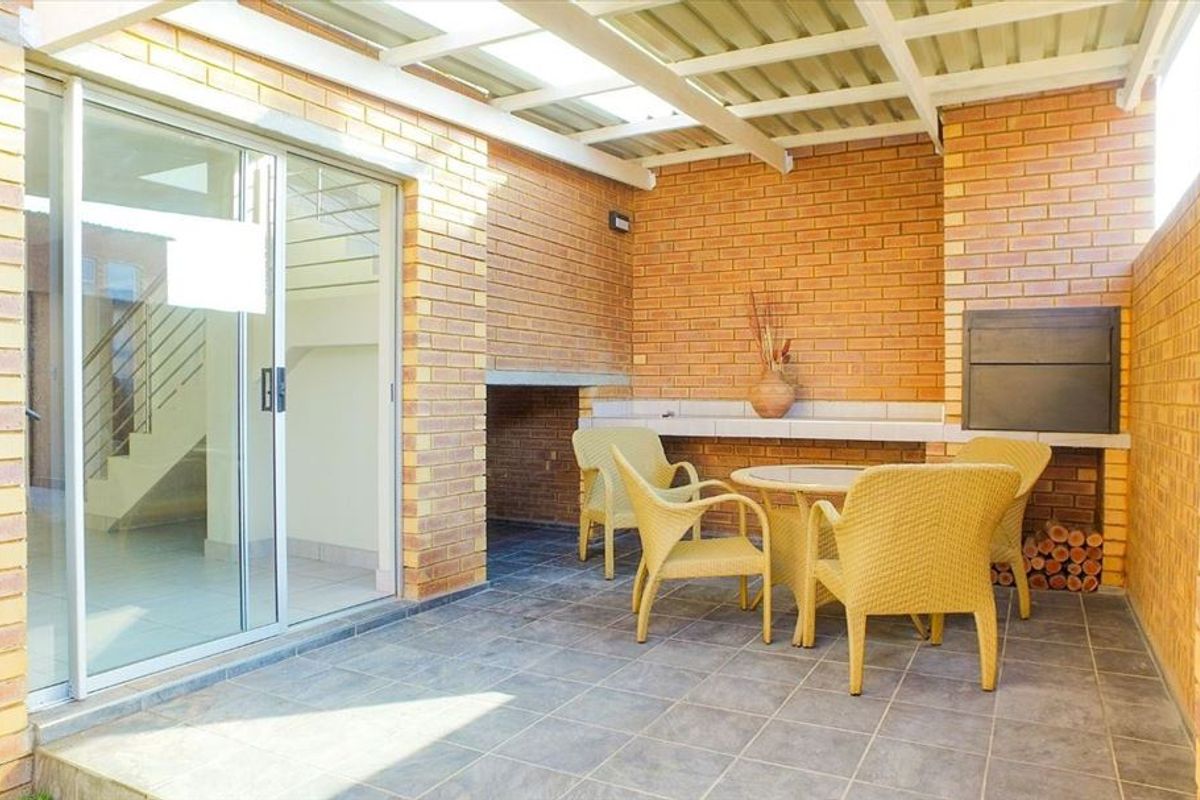 Covered patio area featuring a built-in braai, tiled flooring, and direct access to the interior through a sliding glass door.