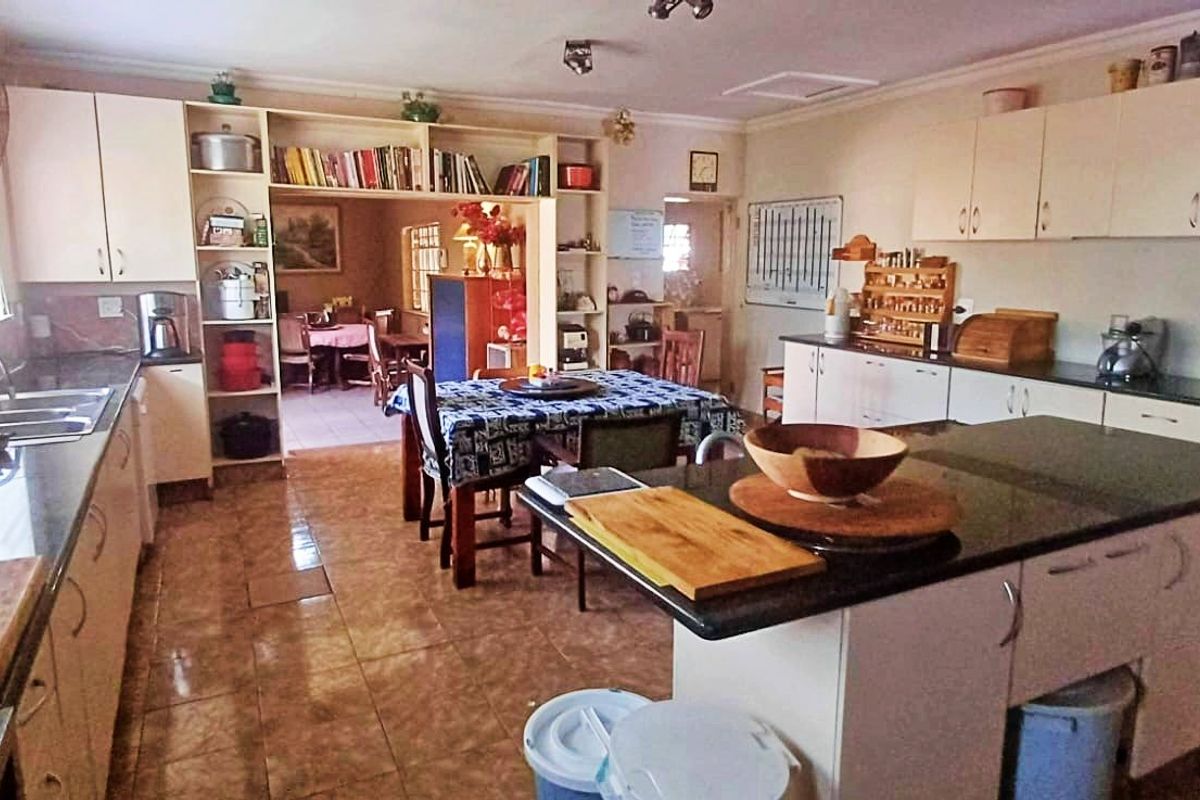 Spacious kitchen featuring granite countertops, ample built-in cabinetry, a central island, and tiled flooring, with an open-plan layout connecting to the dining area.