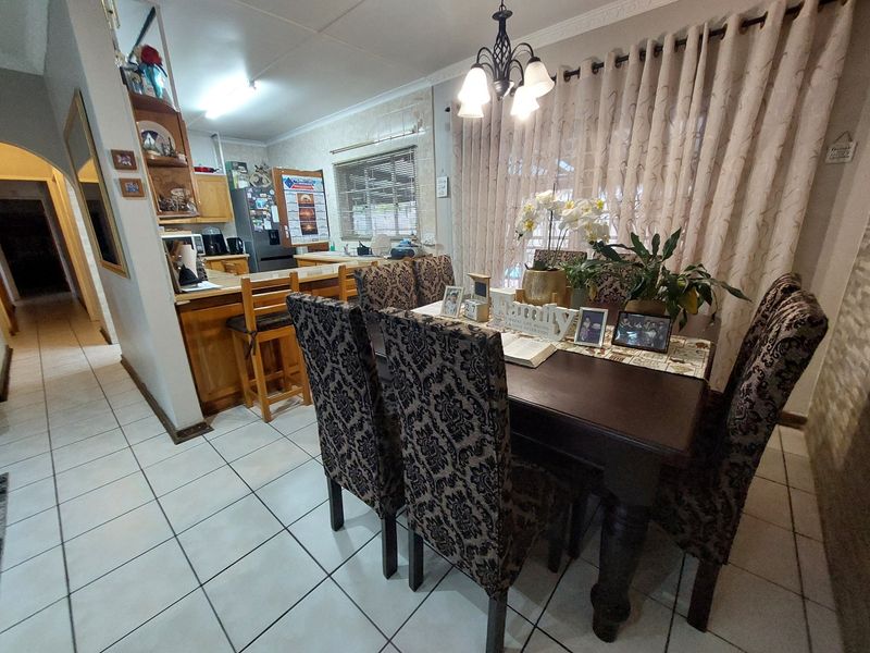 Open-plan dining and kitchen area featuring tiled flooring, built-in cabinetry, and a breakfast counter, creating a functional and connected living space.