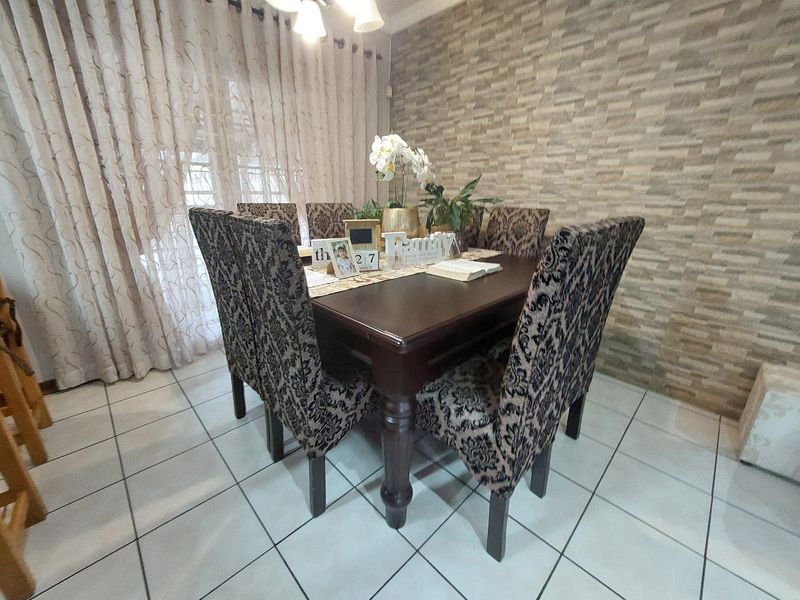Dining room featuring tiled flooring and a textured stone veneer feature wall, providing a defined space for family meals.