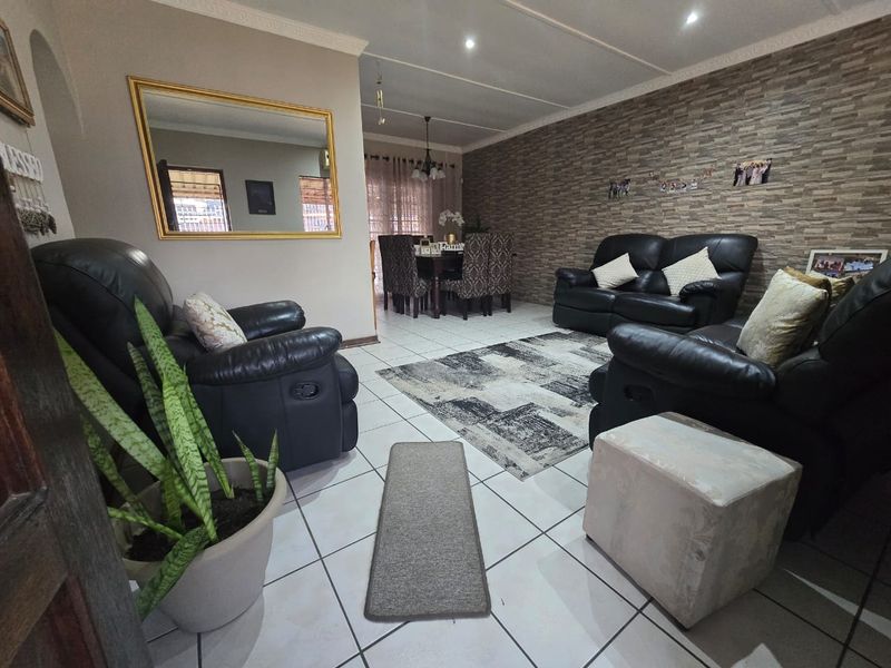 Open-plan living and dining area featuring tiled flooring, a textured stone-cladding feature wall, and recessed downlighting throughout the space.