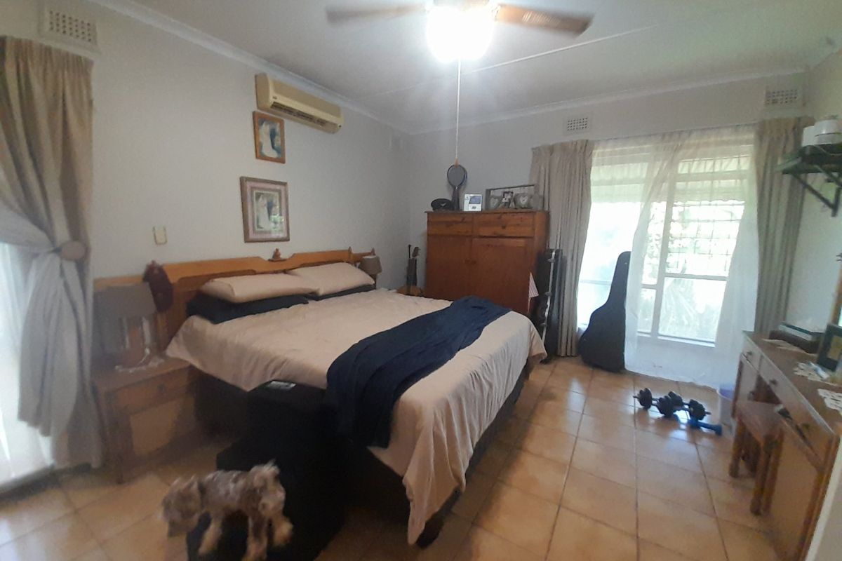 A bedroom featuring tiled flooring, a ceiling fan, and a wall-mounted split-system air conditioner.