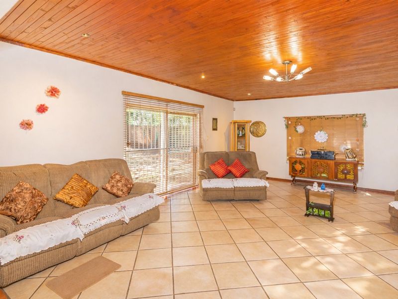 Spacious living room featuring a warm timber tongue and groove ceiling, ceramic tiled flooring, and a sliding glass door providing access to the outdoors.