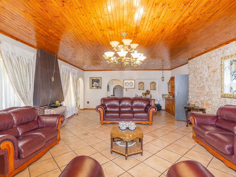 Spacious living room featuring a warm timber tongue and groove ceiling, stone feature wall, tiled flooring, and a built-in fireplace.