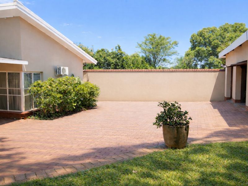 A private rear courtyard featuring paved flooring, a high boundary wall for privacy, and direct access to the main dwelling via sliding glass doors.