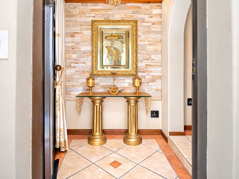A welcoming entrance hall featuring a decorative stone-clad feature wall, tiled flooring, and an elegant arched transition to the adjoining living space.