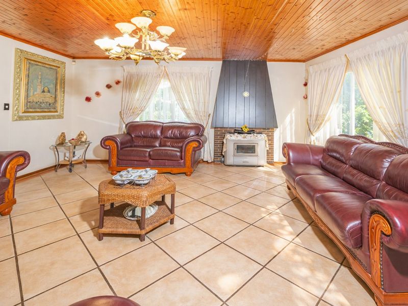 Spacious living room featuring a wood-paneled ceiling, tiled flooring, and a prominent built-in fireplace with a chimney breast.