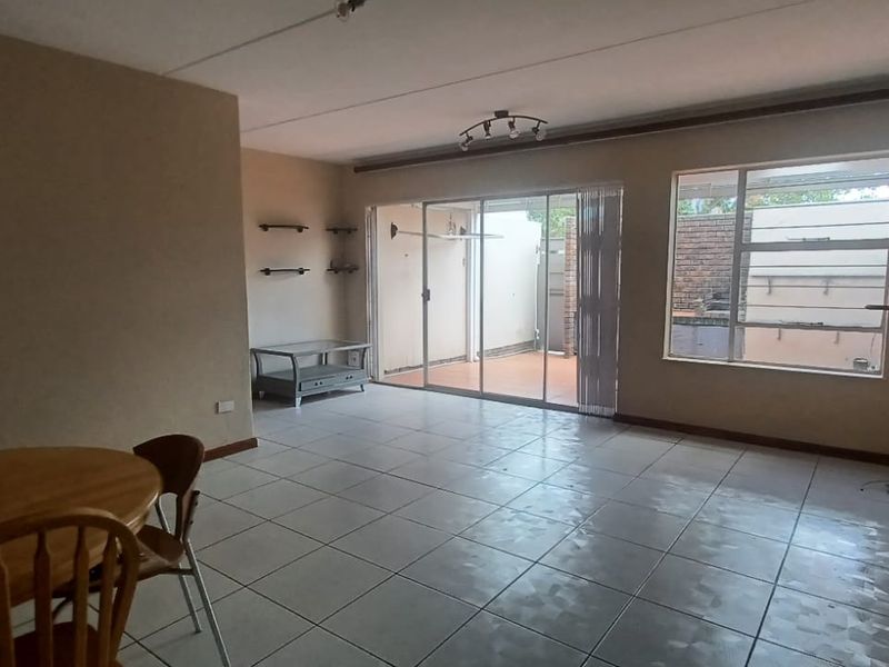 Open plan living and dining area featuring tiled flooring, large windows, and sliding glass doors leading to an outdoor patio space.