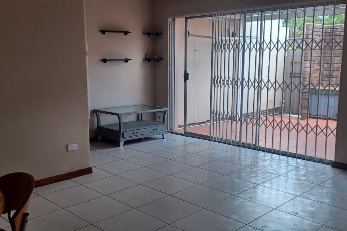 Spacious living area featuring tiled flooring and a sliding glass door with security gate, providing direct access to the outdoor patio area.