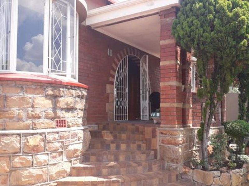 Front entrance of a character home featuring a brick and stone facade, bay window, and a covered porch with tiled steps.