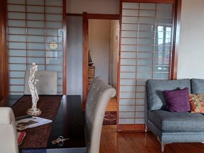 A living area featuring polished timber flooring and traditional sliding shoji-style room dividers, creating a distinct separation between living and adjacent spaces.