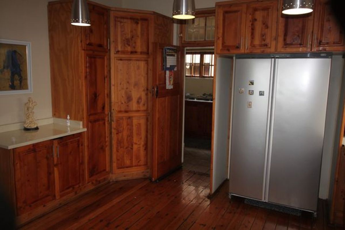 Kitchen featuring traditional wooden cabinetry, stone countertops, and hardwood flooring, with a view into an adjacent scullery area.