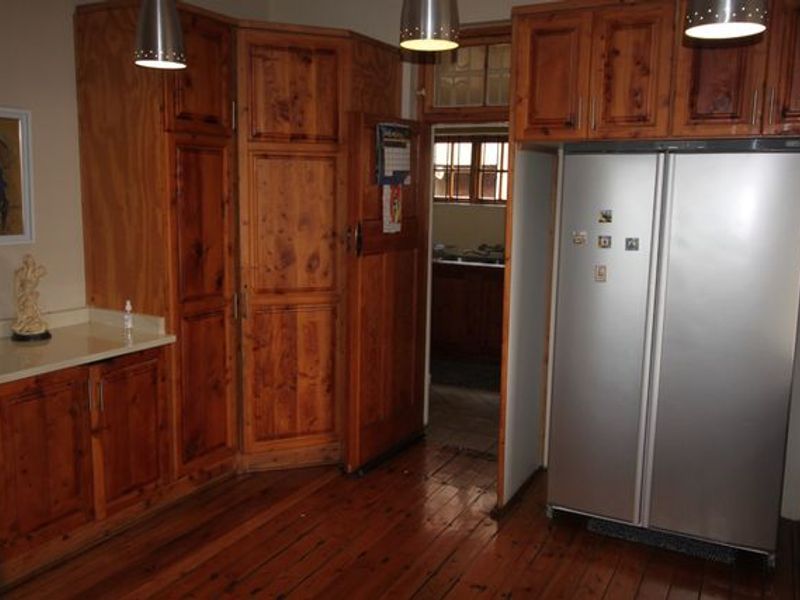 Kitchen featuring traditional wooden cabinetry, stone countertops, and hardwood flooring, with a view into an adjacent scullery area.