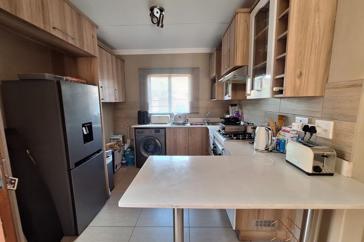 Functional kitchen featuring wood-look cabinetry, tiled backsplash, gas hob with extractor, and a convenient breakfast bar area.
