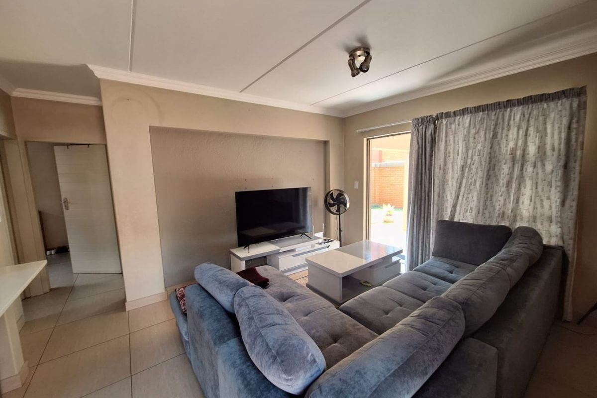 A living room featuring tiled flooring, a sliding glass door providing outdoor access, and a coved ceiling cornice.