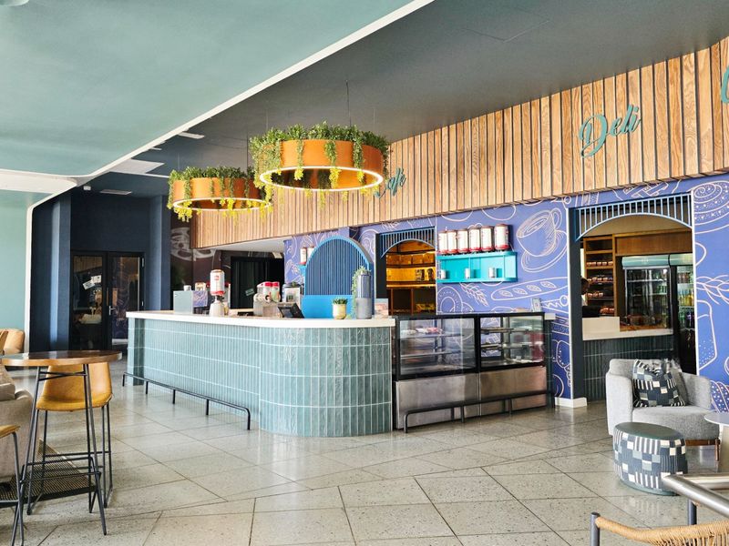 A modern open-plan commercial space featuring a tiled service counter, decorative wall paneling, and integrated display units, suitable for a cafe or deli.
