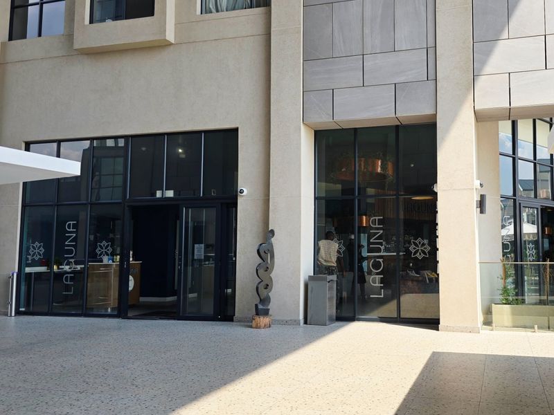 Modern commercial storefront entrance featuring stone cladding, large glass panels, and clean terrazzo flooring, presenting a professional and well-maintained exterior facade.