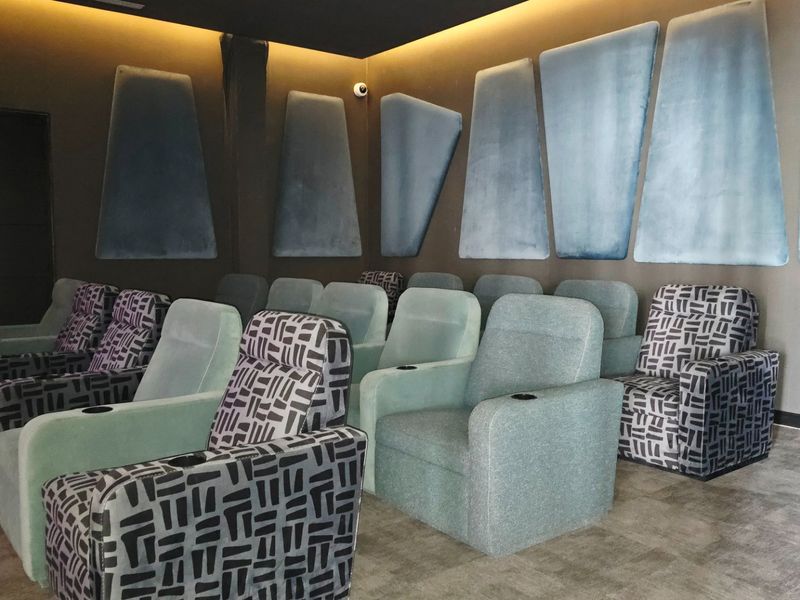 A dedicated cinema room featuring tiered seating, acoustic wall paneling, and recessed ambient lighting for an immersive viewing experience.