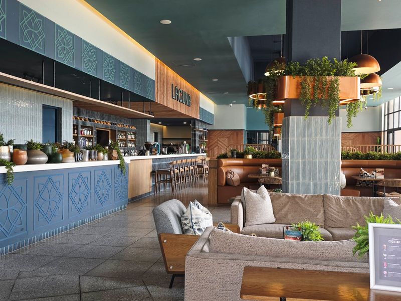 A modern, well-appointed bar area featuring a long service counter, built-in booth seating, stylish tiled flooring, and sophisticated decorative wall and ceiling finishes.